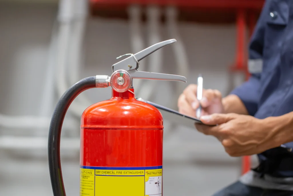 A worker inspecting a fire extinguisher